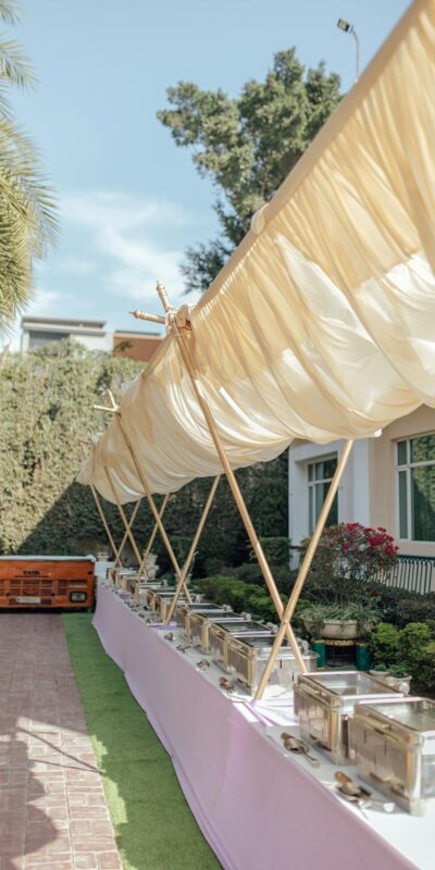 Charming outdoor buffet arrangement under canopy at garden event, perfect for weddings or celebrations.