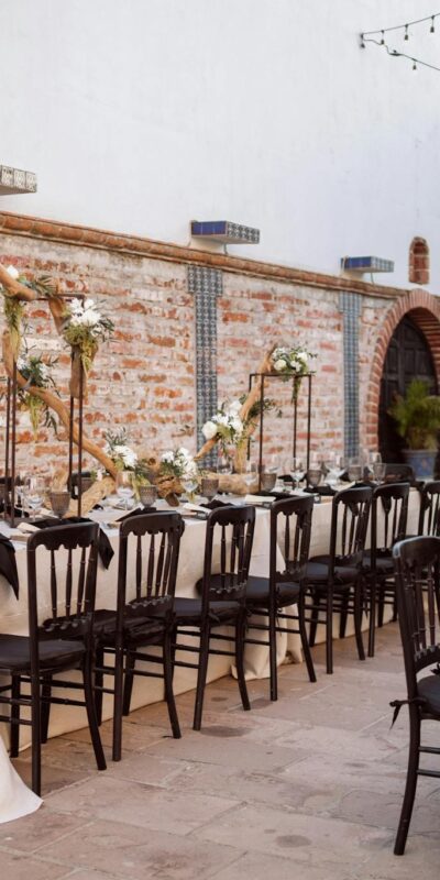 Chic outdoor wedding venue with decorated tables, chairs, and floral arrangements.